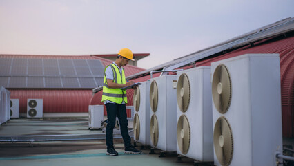 Engineers is checking the air conditioning cooling system of a major building or industrial facility. Background is solar cell on the roof. © NewSaetiew