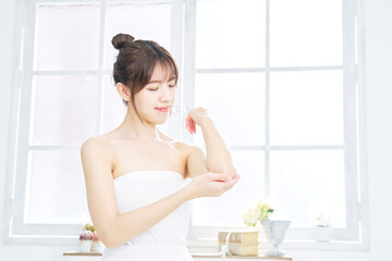 リビングで肘のスキンケアをする女性