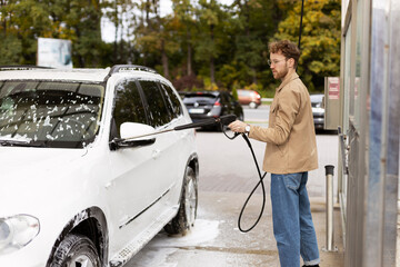 Man washing his car in a self-service car wash station. Car washing service concept