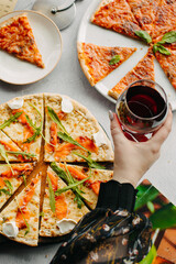 Traditional Italian pizza, vegetables, ingredients on a light background.Top view. a piece of pizza in the hand.Festive table. company of friends