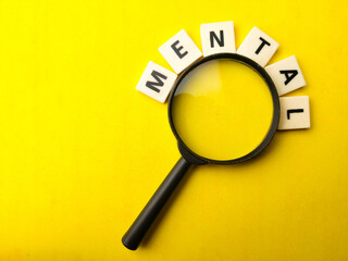 Magnifying glass and toys word with word MENTAL on yellow background.