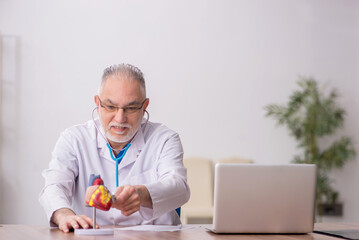 Old male doctor cardiologist working in the clinic