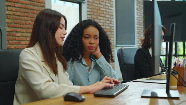 A team of female designers are collaborating on a project, brainstorming together and conducting research on their computer to gather data and information.