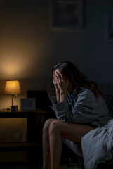 Young Asian woman in bedroom feeling sad tired and worried suffering depression in mental health, woman sitting in bed cannot sleep from insomnia. - 590687941
