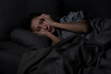 Fototapeta na wymiar Depressed young Asian woman lying in bed cannot sleep from insomnia