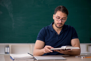 Young male teacher sitting in the classroom