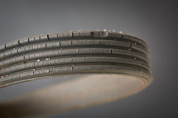 close-up of old used and worn out vehicle drive belt, isolated on gray background, failed and...