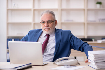 Obraz premium Old male employee and too much work at workplace