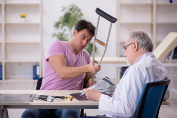 Obraz premium Young leg injured patient visiting old male doctor radiologist