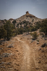 Curvy dirt trail through desert terrain in spring in central Utah near Goblin Valley underneath a...