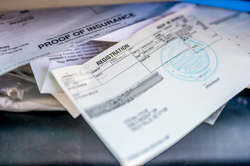Proof of insurance and vehicle registration documents in the glove compartment of a car. 