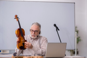 Old male music teacher in the classroom