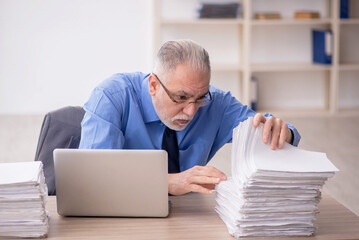 Obraz premium Old male employee and too much work in the office