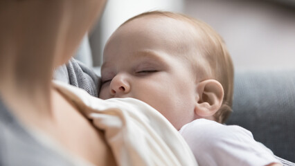 New mom breastfeeding calm peaceful sleepy infant with closed eyes, holding sleeping little baby in...