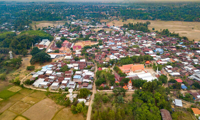 Top view Aerial photo from flying drone over Beautiful green rice field and village from above.The road passes through small villages and leads to green rice fields.OLd house in the northeastern Thai.