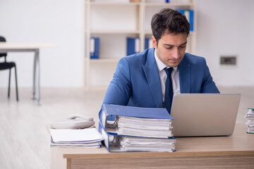 Young male employee and too much work in the office