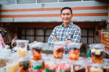 young man sell mix fruit drink and jelly juice. street food vendor sell some traditional fruit beverage on plastic cup with colorful color