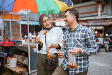 couple have fun enjoying snacks from street vendor shop during fasting in ramadan