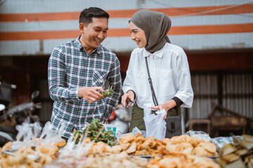 Fototapeta na wymiar beautiful muslim couple are shopping in a food stall or street vendor during ramadan