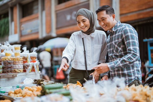 beautiful muslim woman and man are shopping in a food stall or street vendor during ramadan