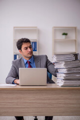 Young male employee and too much work in the office