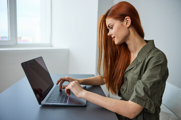 woman in bright office typing puzzled at laptop while working full time