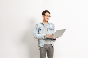 A man working with his laptop on his hand. Indonesian or southeast asian model isolated with white wall background.