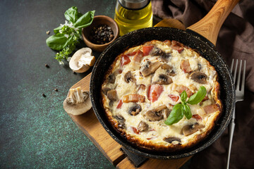 Frittata is an Italian breakfast dish. Omelette with mushrooms and bacon on a dark stone table. Copy space.