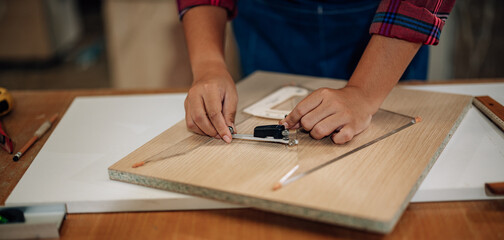 A Carpenter carefully measures, marks dimensions, and lays out reference lines on wood using scribe, divider, square, ruler, and caliper. The woodworking process need skills, experience, precision.