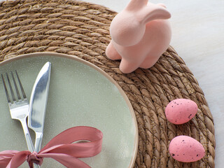 Festive Easter table setting with eggs, bunny and flowers on light background, flat lay. Elegance pastel and pink tablescapes. Easter celebration. Delicate Easter composition. View from above.