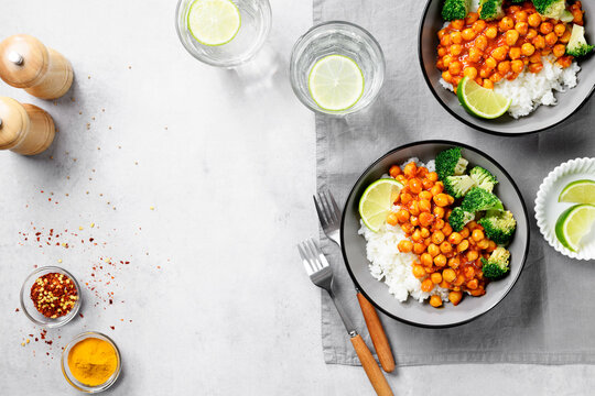 Chickpea curry with basmati rice and broccoli on gray background, top view
