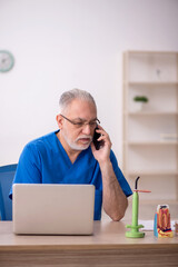 Old male dentist working in the clinic