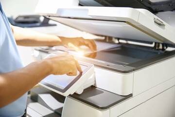 Photocopier printer, Close up hand office man press copy button on panel to using the copier or photocopy machine for scanning document or printing paper or Xerox a sheet. - obrazy, fototapety, plakaty