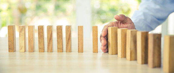 Close-up hand prevent wooden block not falling domino concepts of financial risk management and...