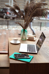 Workplace in cafe. Laptop, note book and coffee near window in cafe