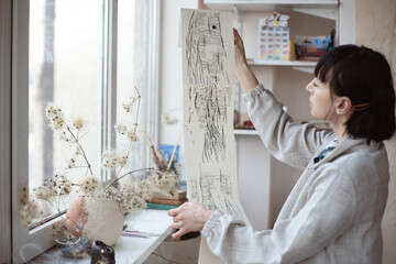 female artist look at her work drawing with pen and black ink. Graphic Painting. Creating modern Art
