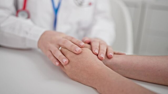 Two women doctor and patient supporting with hands together at clinic