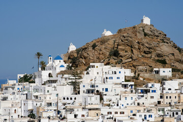 Panoramic view of a church, smaller chapels and the Greek flag on the top of a hill overlooking the...