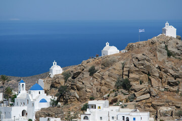 Panoramic view of a church, smaller chapels and the Greek flag on the top of a hill overlooking the...