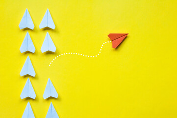 Red paper airplane origami leaving other white airplanes on yellow background with customizable...