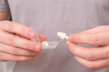 man inserts earplugs so as not hear extraneous noise, music, snoring. Silicone earplugs for sleeping