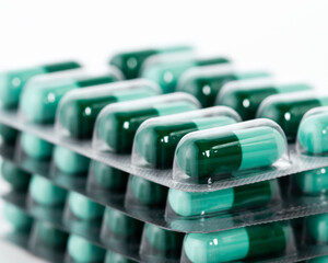 Green pills in plastic package close up. Pharmaceutical industry concept.