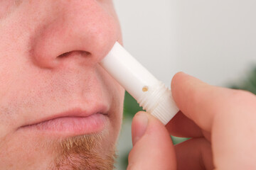 Adult man uses nasal stick inhaler to smell for relieve dizzy and faint symptoms.