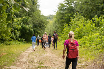 Fototapeta premium Group of hikers with backpacks climbing up mountains