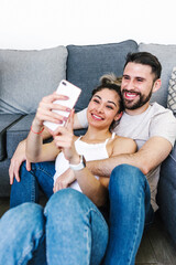 latin couple of young man and woman taking a photo selfie with mobile phone at home in Mexico Latin America
