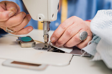 Atelier process needle detail. Unrecognizable woman hand on a sewing machine doing handmade fabric