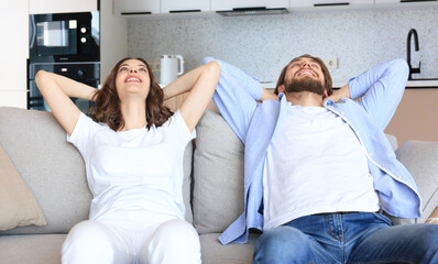 Happy smiling beautiful couple sitting on a sofa and dreaming about new home.