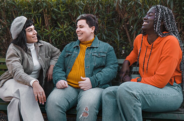 Diverse Friends Relaxing in Park - three young friends, a brunette woman, a non-binary plus size...