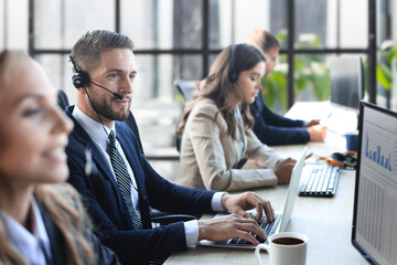 Portrait of call center worker accompanied by her team. Smiling customer support operator at work.