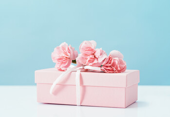 Pink gift box with tender pink carnation flowers. Blue background. Gift or holiday concept. Mothers...